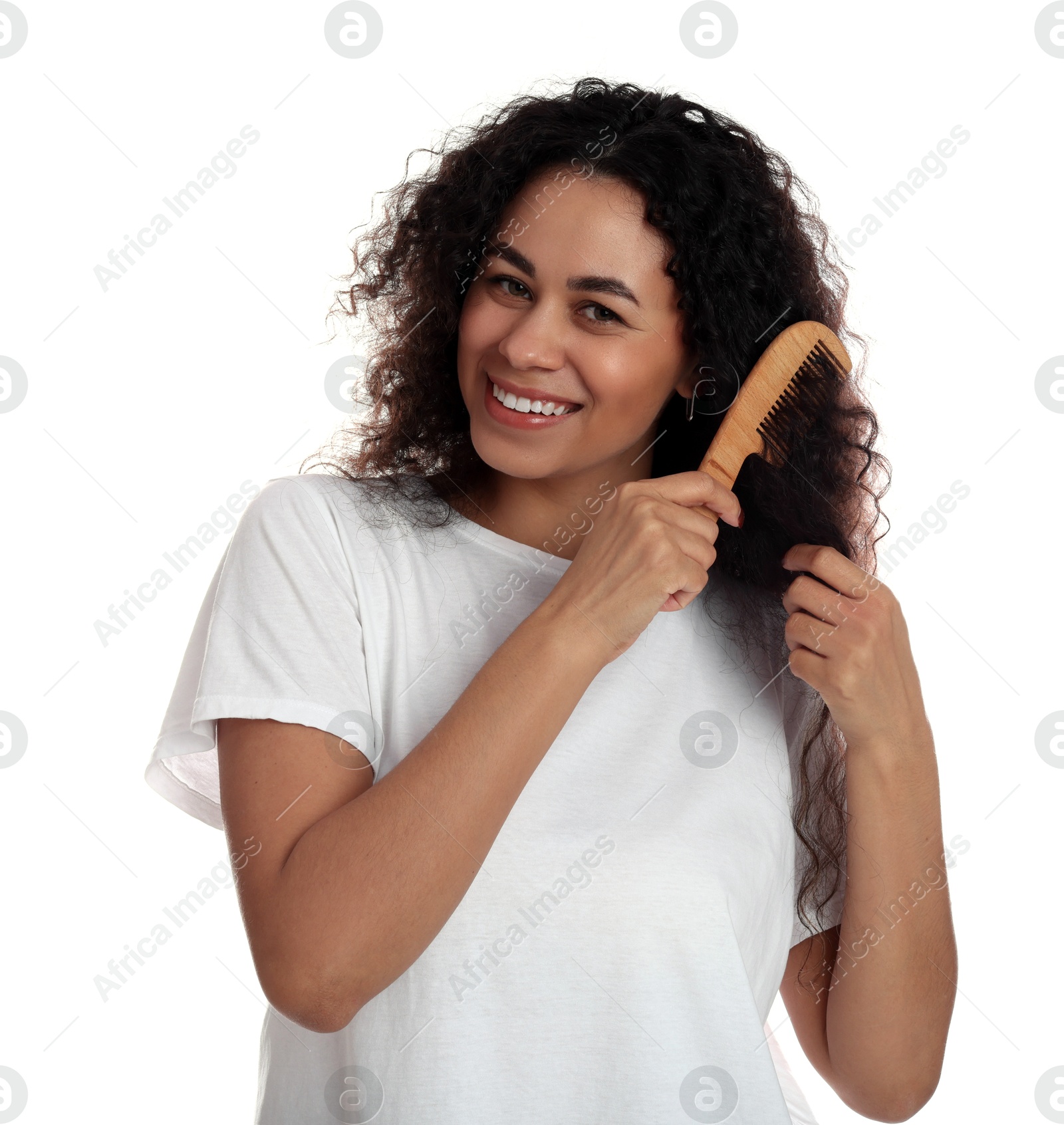 Photo of Smiling young woman brushing her curly hair with comb on white background