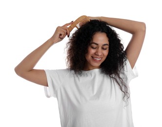 Photo of Smiling young woman brushing her curly hair with comb on white background