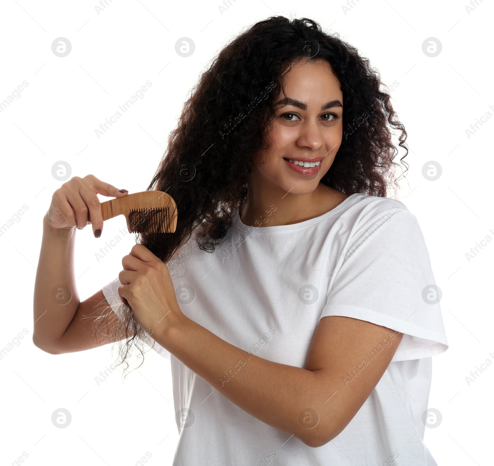 Photo of Smiling young woman brushing her curly hair with comb on white background