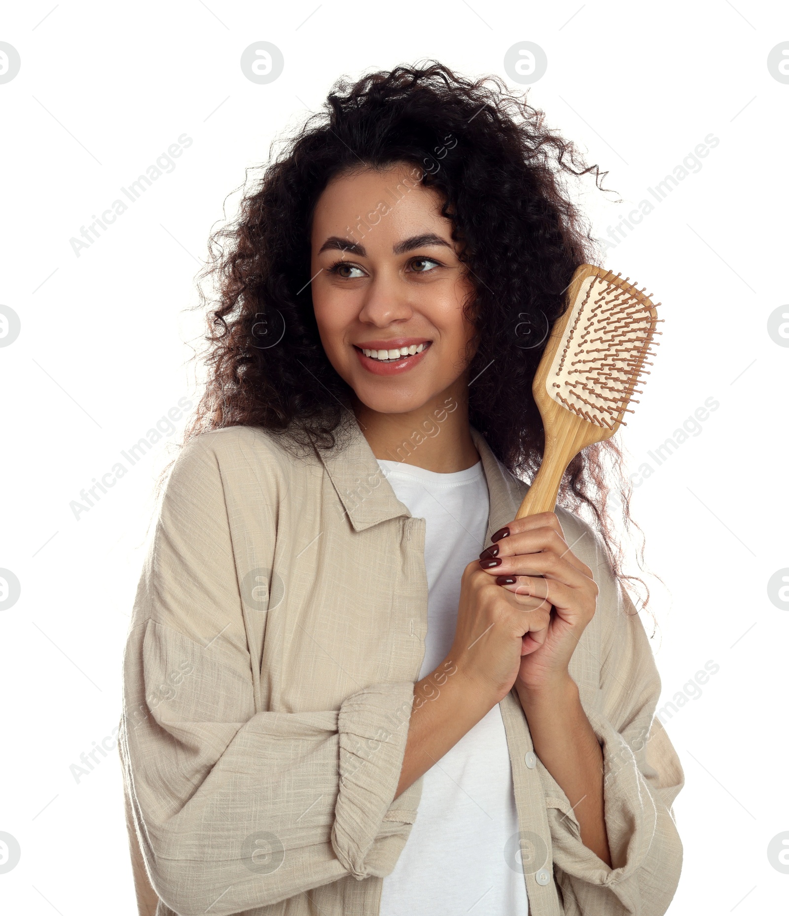 Photo of Smiling young woman with curly hair holding wooden brush on white background