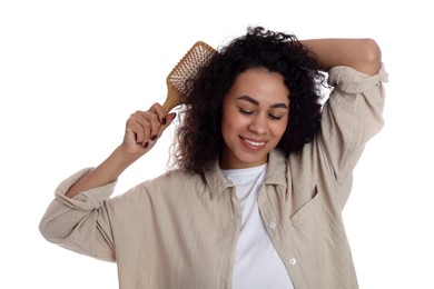 Photo of Smiling young woman brushing her curly hair on white background