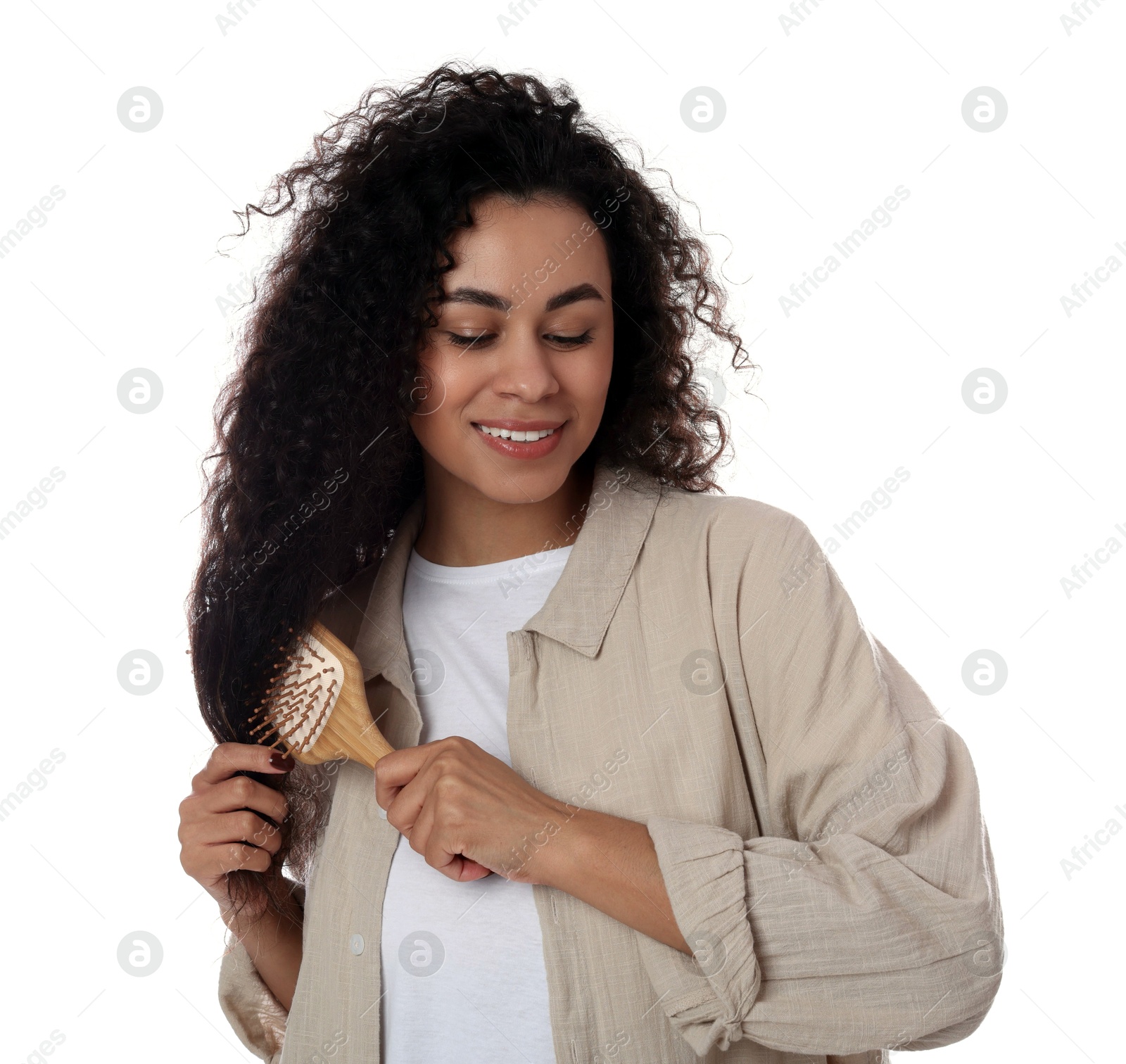 Photo of Smiling young woman brushing her curly hair on white background