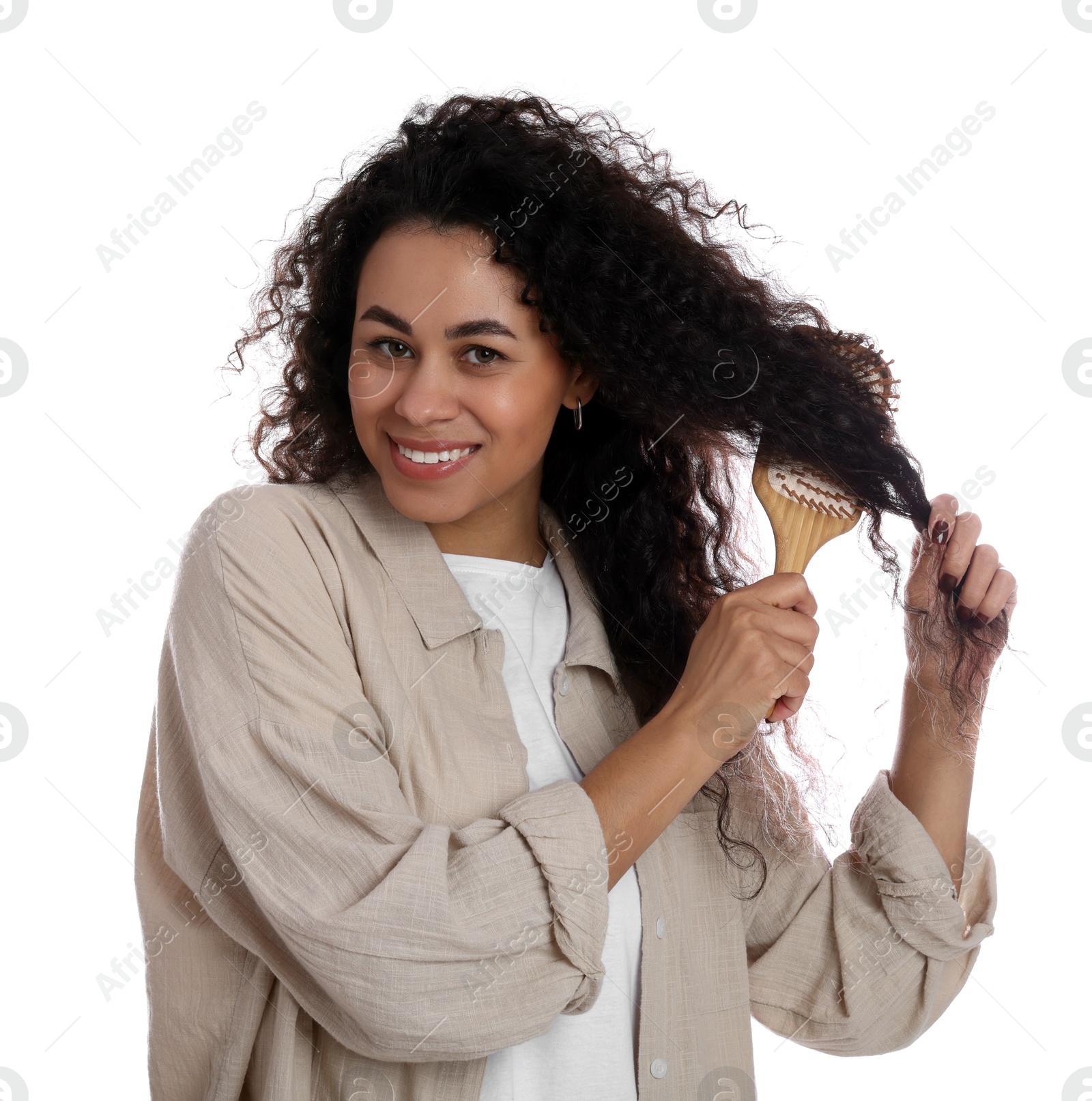 Photo of Smiling young woman brushing her curly hair on white background