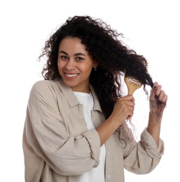 Photo of Smiling young woman brushing her curly hair on white background