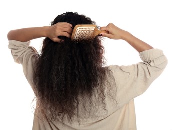 Photo of Woman brushing her curly hair on white background, back view