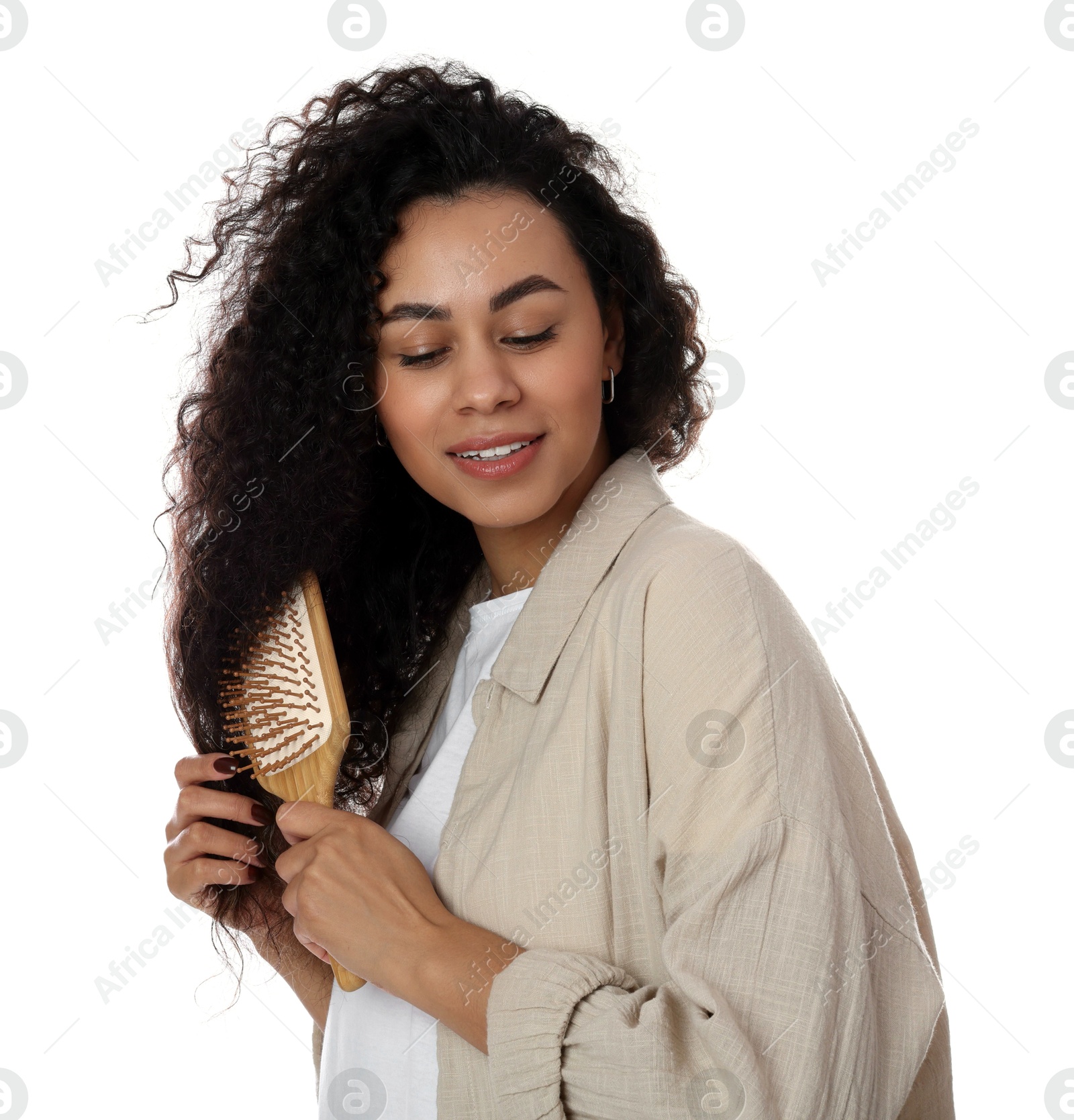 Photo of Smiling young woman brushing her curly hair on white background