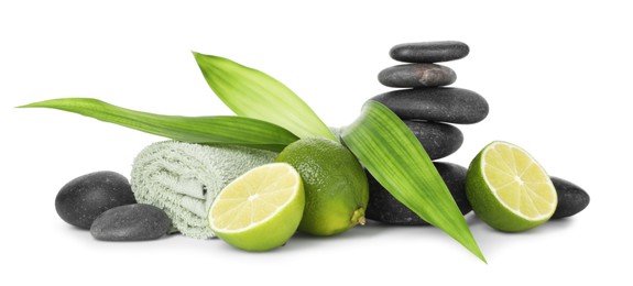Photo of Spa composition with limes, towel, massage stones and green leaves isolated on white