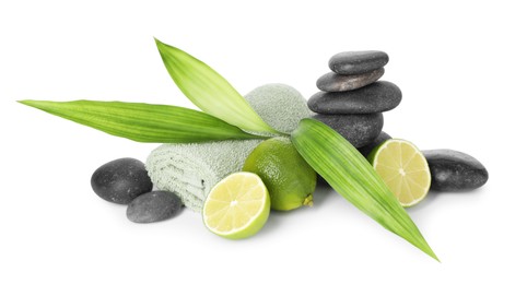 Photo of Spa composition with limes, towel, massage stones and green leaves isolated on white