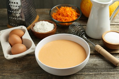 Photo of Bowl with dough and ingredients for pumpkin pancakes on wooden table