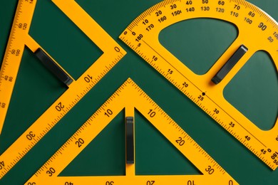 Protractor and triangle rulers on green chalkboard, flat lay