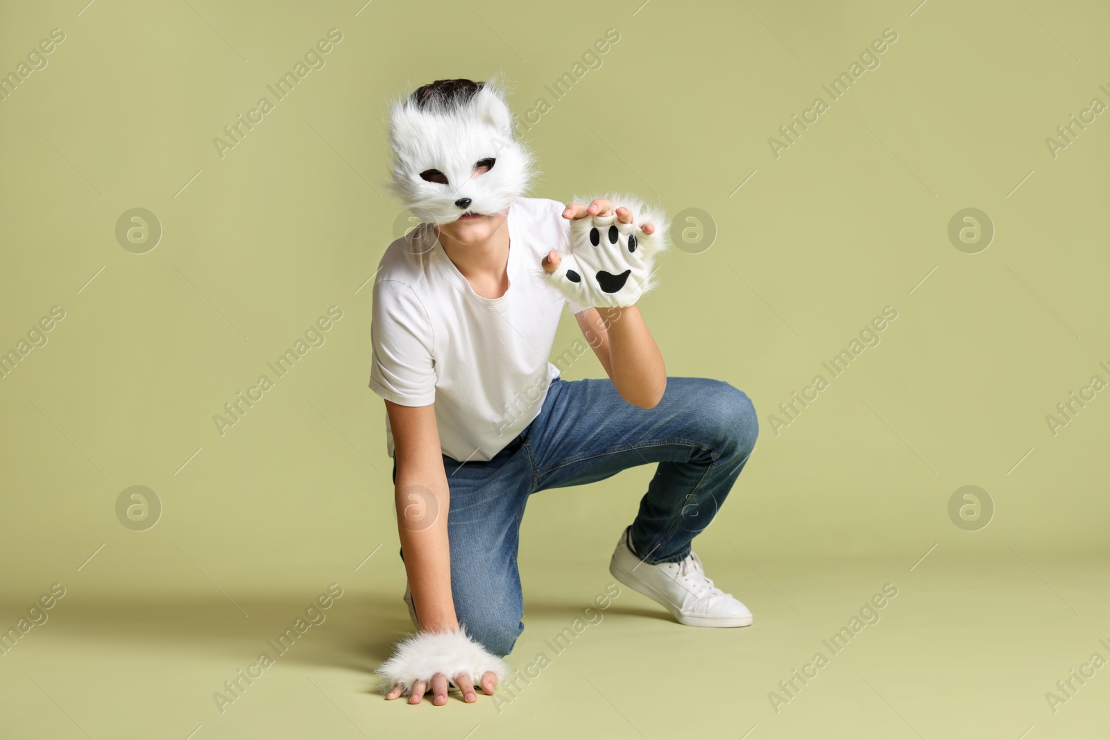 Photo of Quadrobics. Boy wearing cat mask and gloves on pale olive background