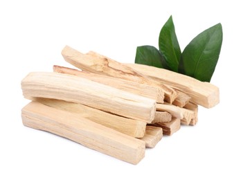 Photo of Pile of palo santo sticks and green leaves on white background