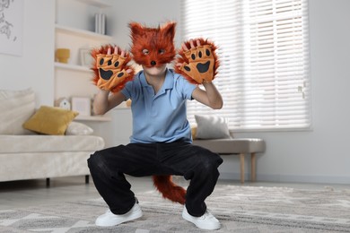 Photo of Quadrobics. Boy wearing fox mask, tail and gloves at home