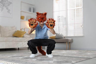 Photo of Quadrobics. Boy wearing fox mask, tail and gloves at home