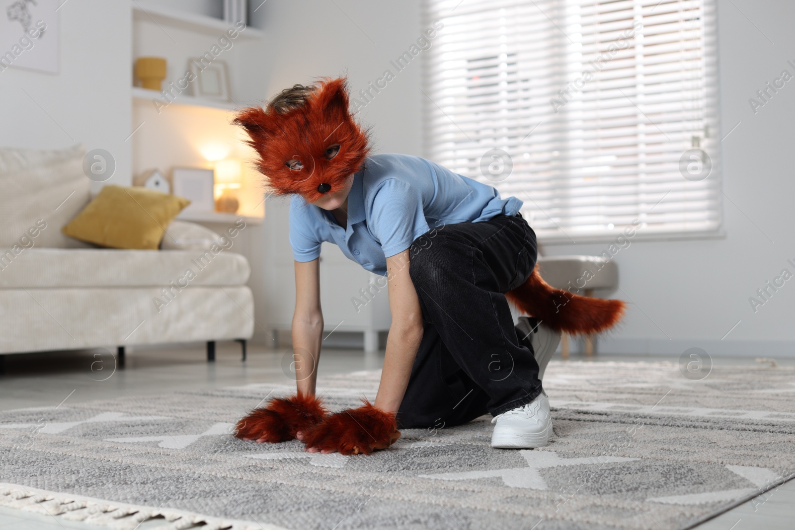 Photo of Quadrobics. Boy wearing fox mask, tail and gloves at home