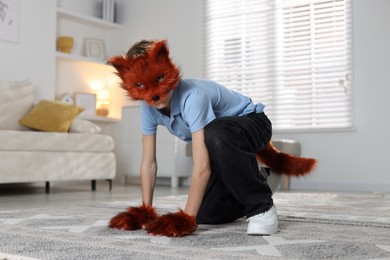 Photo of Quadrobics. Boy wearing fox mask, tail and gloves at home