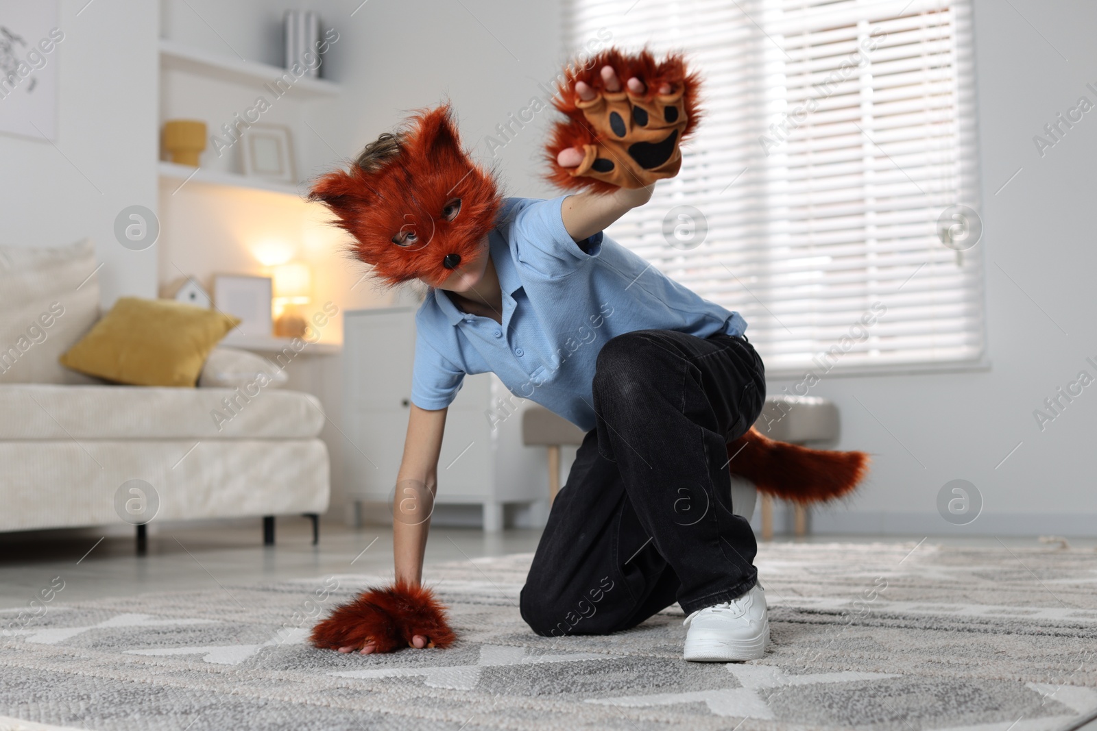 Photo of Quadrobics. Boy wearing fox mask, tail and gloves at home