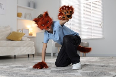 Quadrobics. Boy wearing fox mask, tail and gloves at home