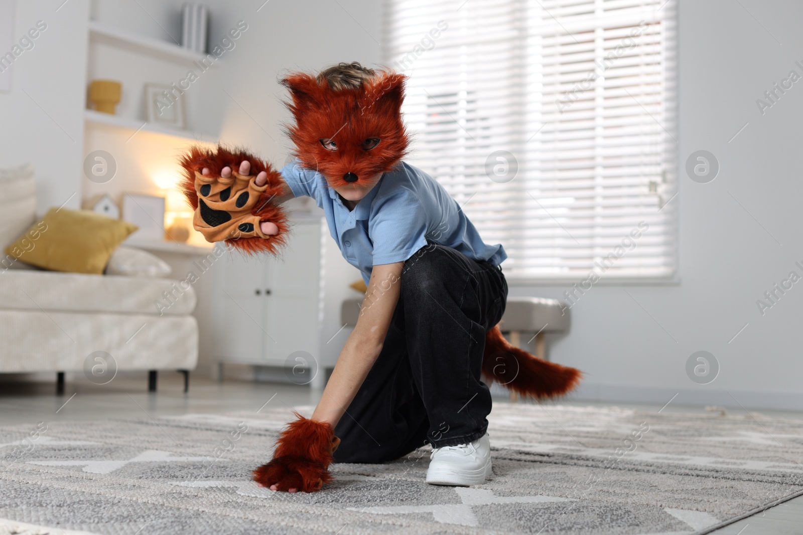 Photo of Quadrobics. Boy wearing fox mask, tail and gloves at home