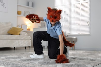 Photo of Quadrobics. Boy wearing fox mask, tail and gloves at home