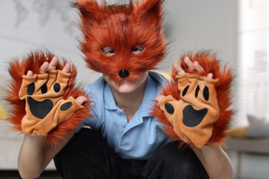 Photo of Quadrobics. Boy wearing fox mask and gloves at home