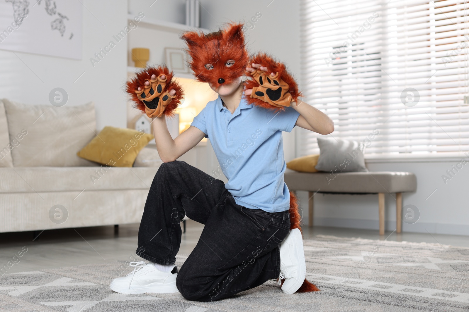 Photo of Quadrobics. Boy wearing fox mask, tail and gloves at home