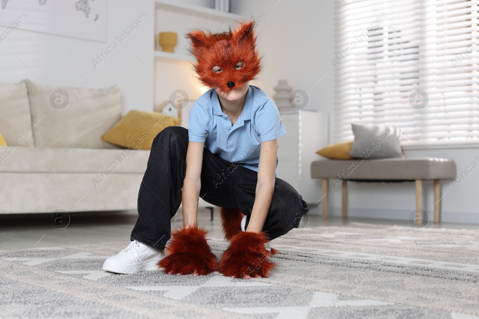 Photo of Quadrobics. Boy wearing fox mask, tail and gloves at home