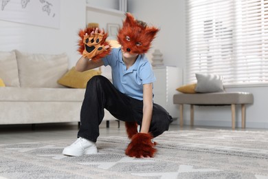 Photo of Quadrobics. Boy wearing fox mask, tail and gloves at home