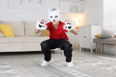 Quadrobics. Boy wearing cat mask and gloves at home