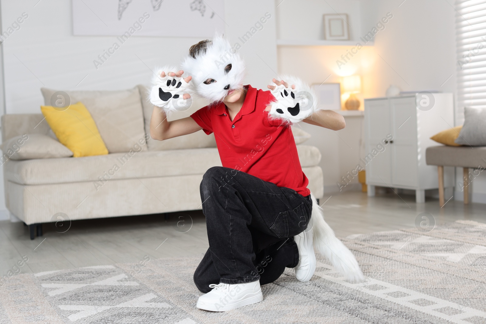 Photo of Quadrobics. Boy wearing cat mask, tail and gloves at home