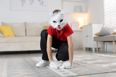 Photo of Quadrobics. Boy wearing cat mask and gloves at home