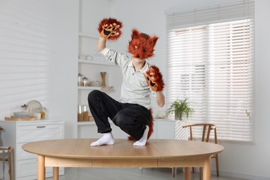 Quadrobics. Boy wearing fox mask and gloves on table indoors