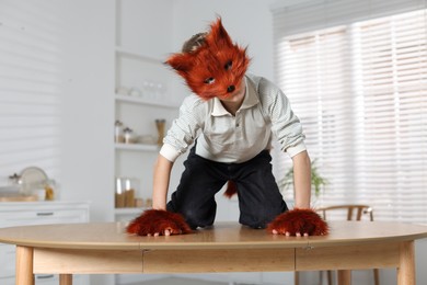 Photo of Quadrobics. Boy wearing fox mask and gloves on table indoors