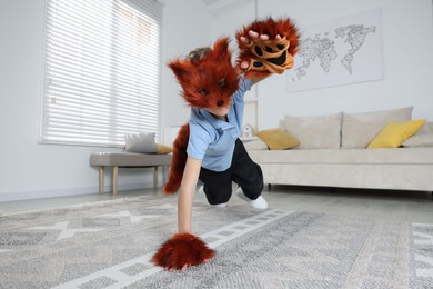 Photo of Quadrobics. Boy wearing fox mask, tail and gloves at home