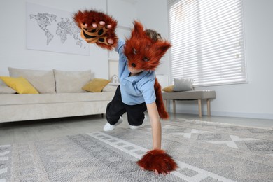 Photo of Quadrobics. Boy wearing fox mask, tail and gloves at home