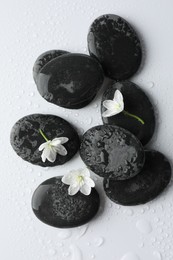 Photo of Wet spa stones and beautiful flowers on white background, flat lay