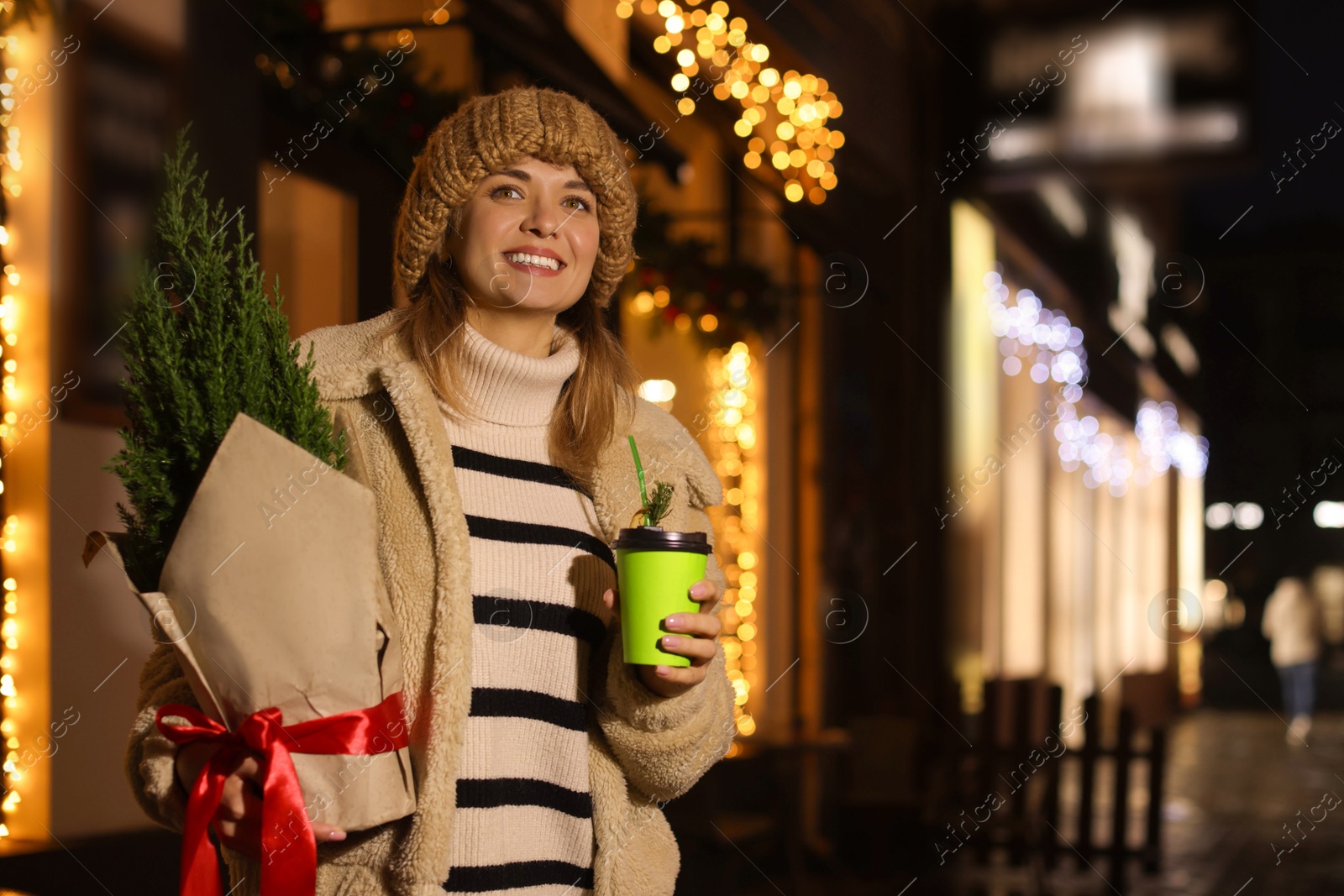 Photo of Happy woman with thuja tree and paper cup outdoors. Space for text