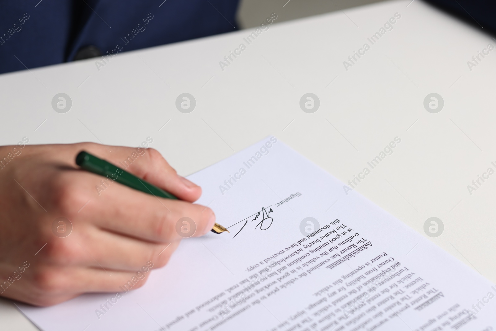 Photo of Man putting signature on document at white table, closeup