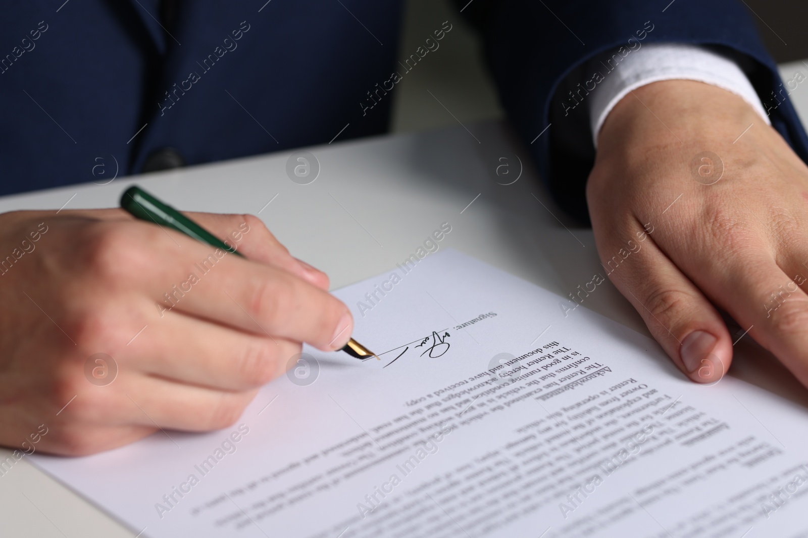 Photo of Man putting signature on document at white table, closeup