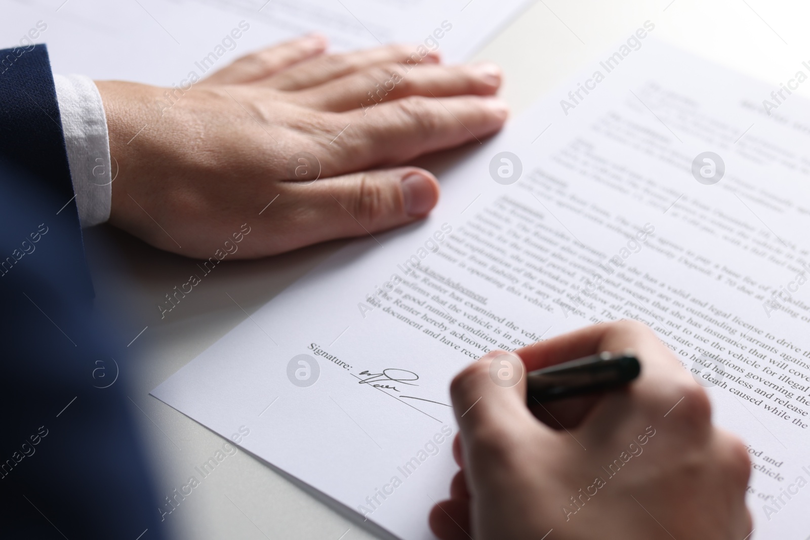 Photo of Man putting signature on document at table, closeup