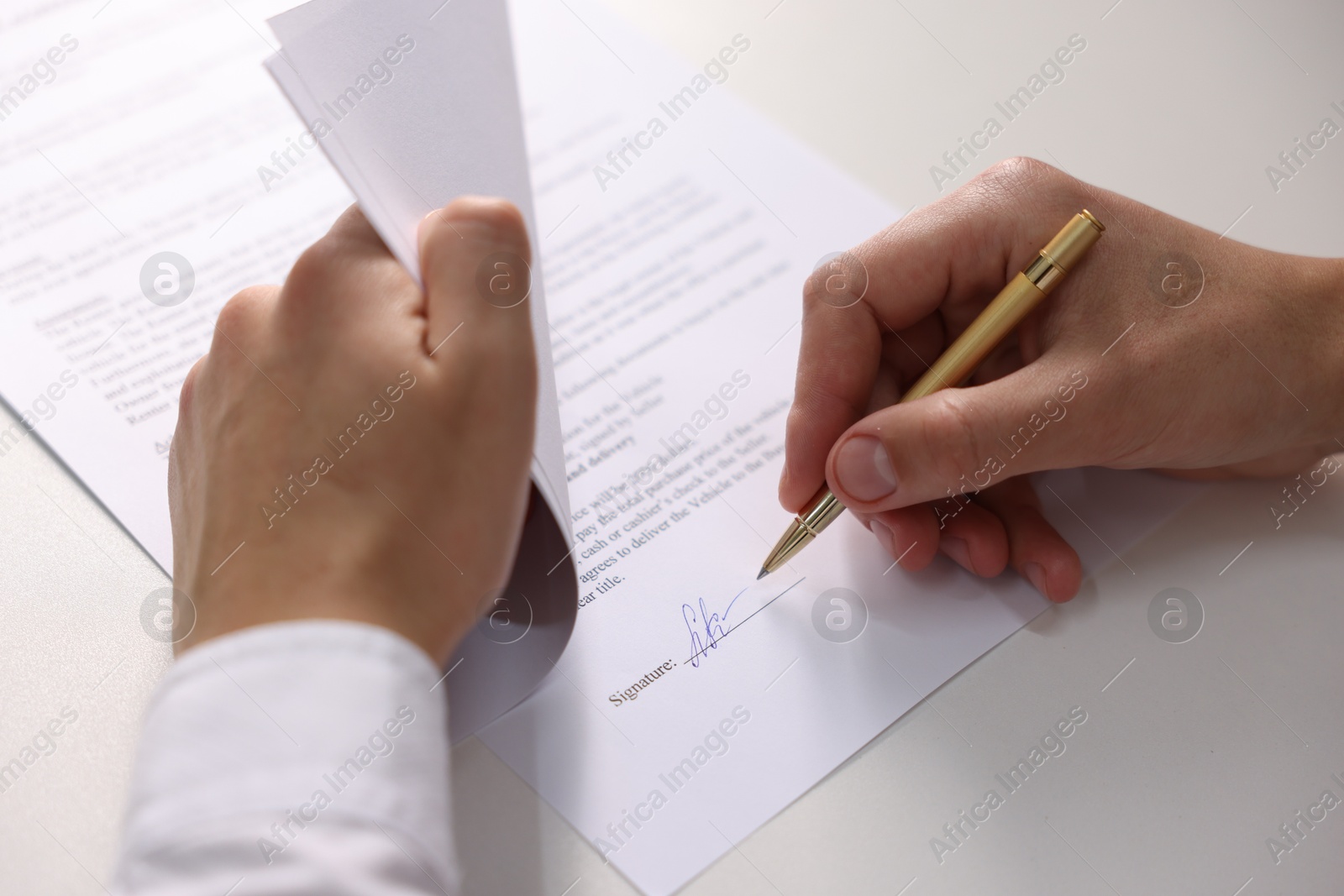 Photo of Man putting signature on document at white table, closeup