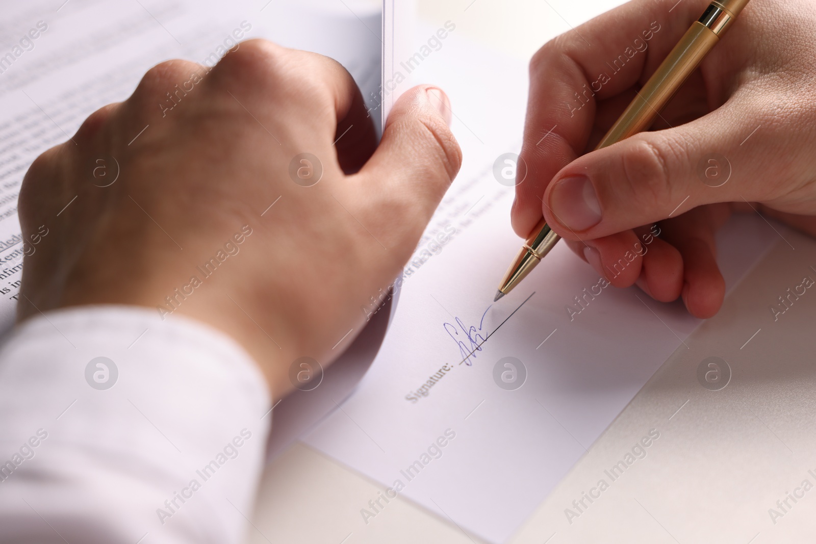 Photo of Man putting signature on document at white table, closeup