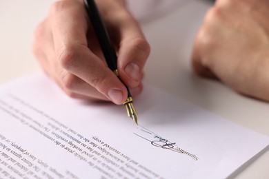 Photo of Man putting signature on document at table, closeup