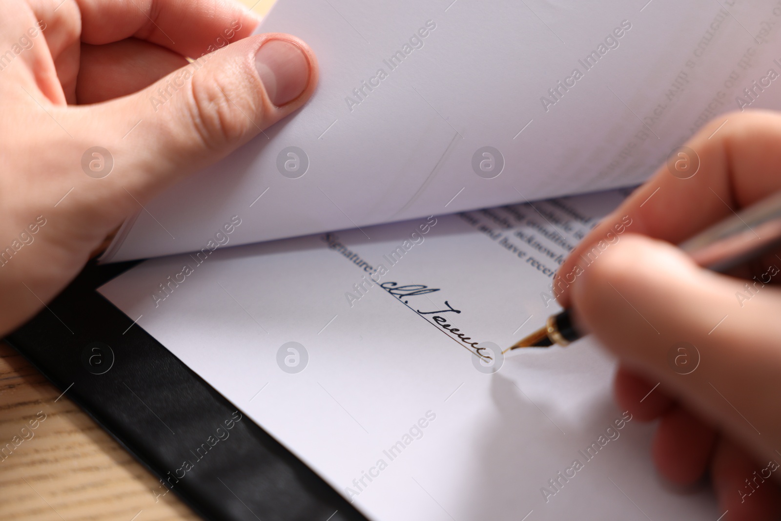 Photo of Man putting signature on document at table, closeup