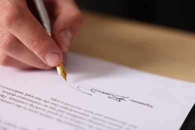 Photo of Man putting signature on document at table, closeup