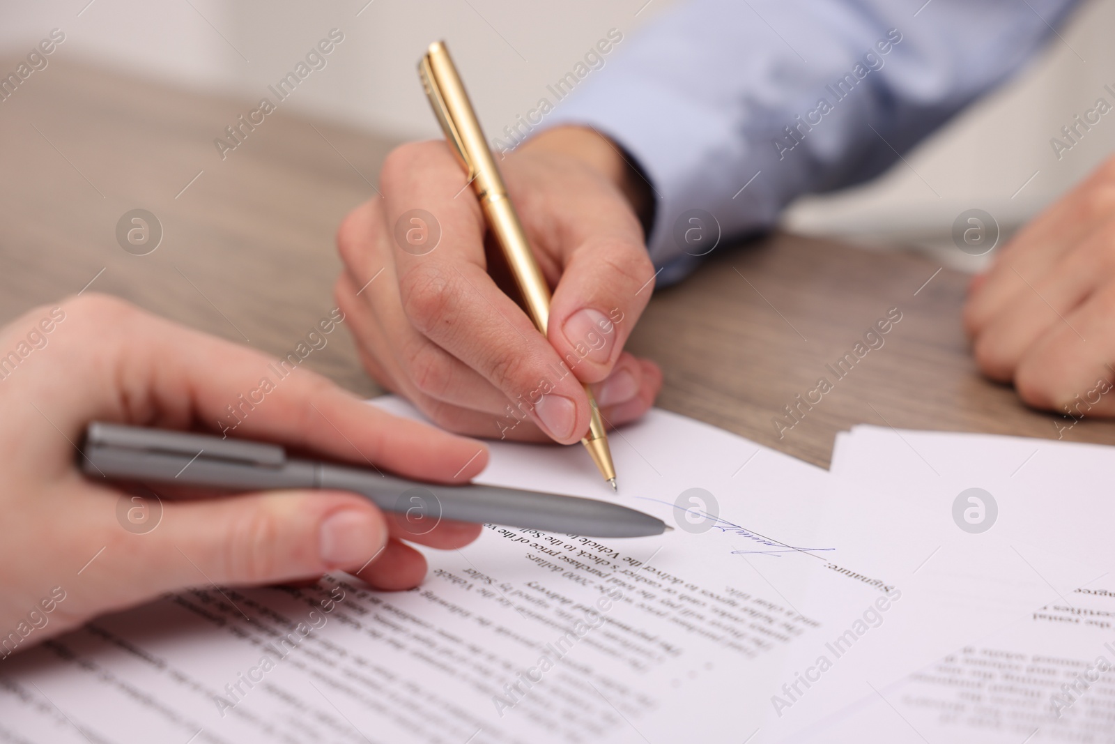 Photo of Woman pointing at document and man putting signature at table, closeup