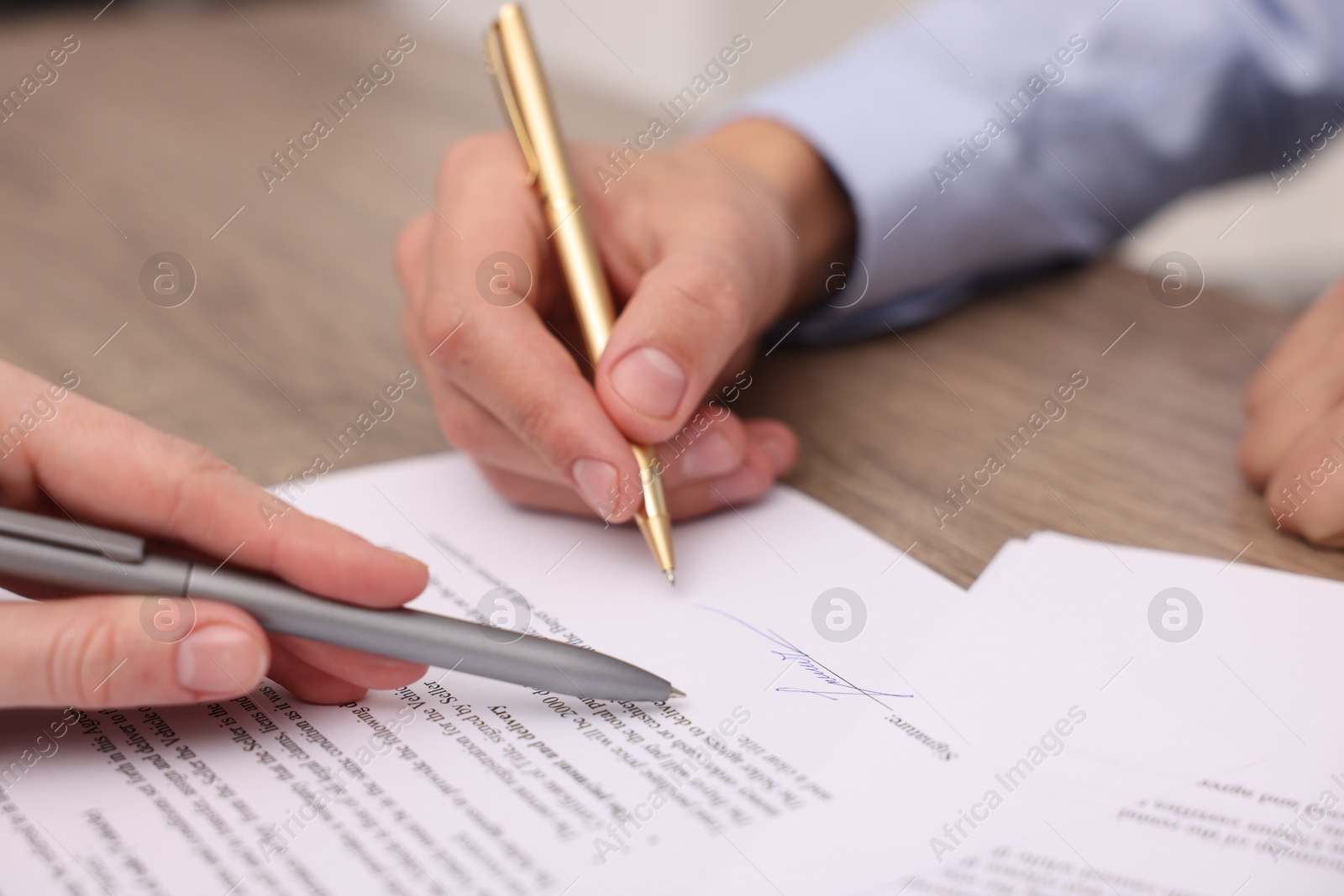 Photo of Woman pointing at document and man putting signature at table, closeup