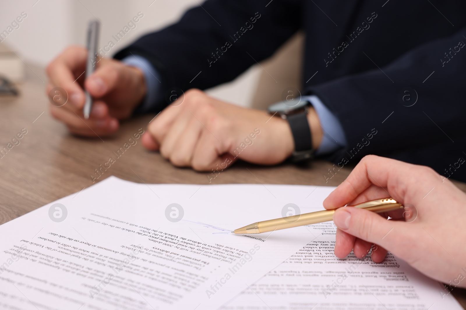 Photo of Woman pointing at signature on document at table, closeup