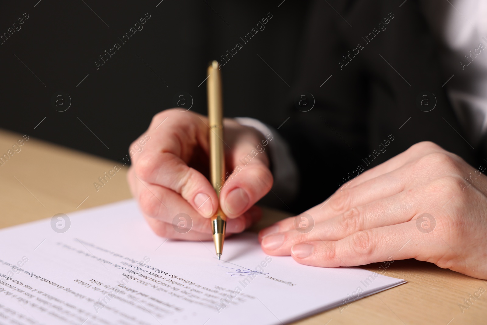 Photo of Woman putting signature on document at table, closeup