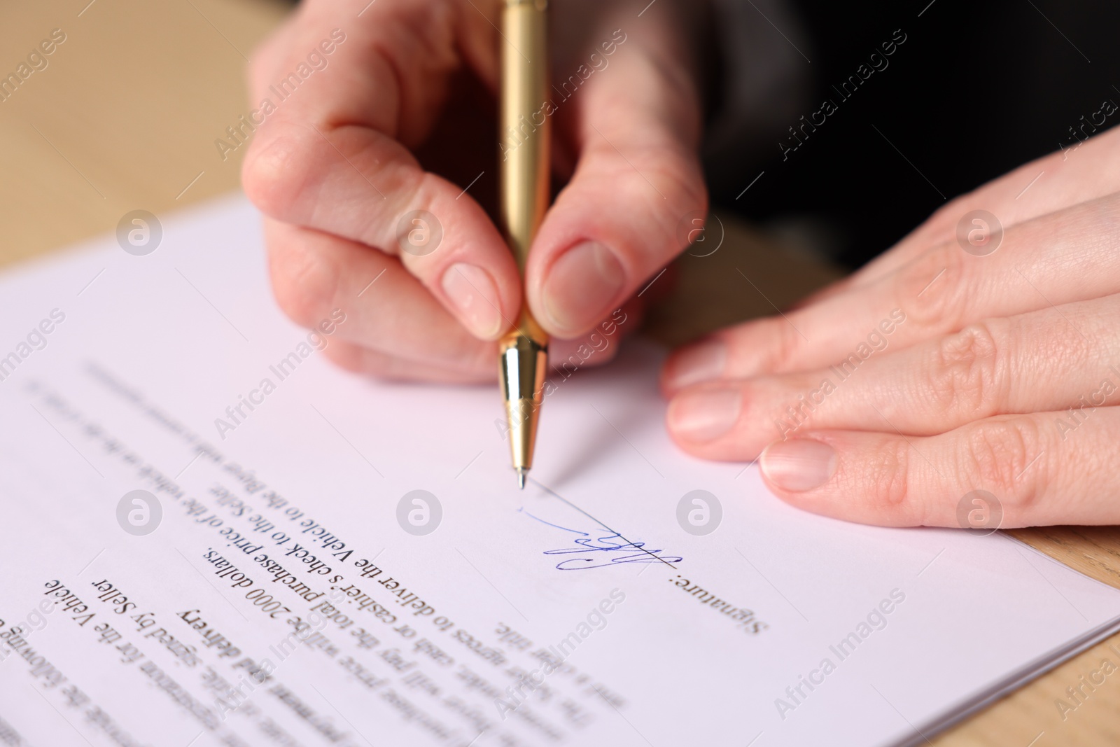 Photo of Woman putting signature on document at table, closeup